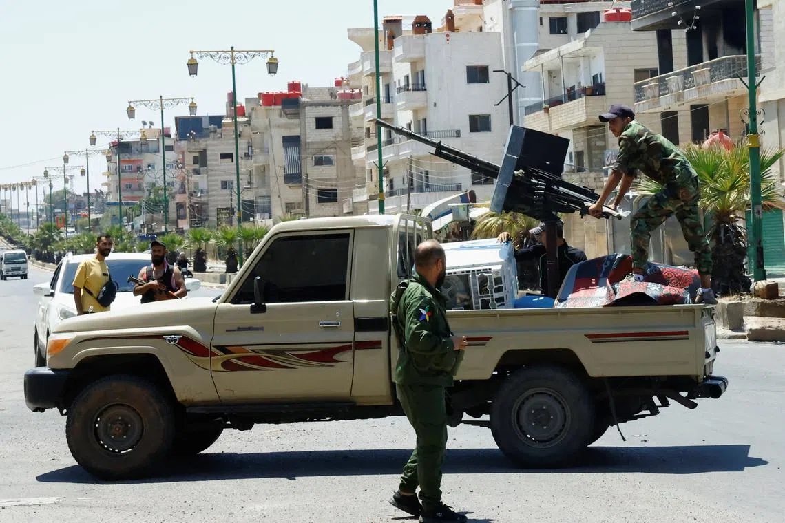 A person wearing military clothing stands at the back of a vehicle, following deadly clashes between Druze fighters, Sunni Bedouin tribes and government forces, in Syria's predominantly Druze city of Sweida, Syria July 25, 2025. REUTERS/Yamam al Shaar