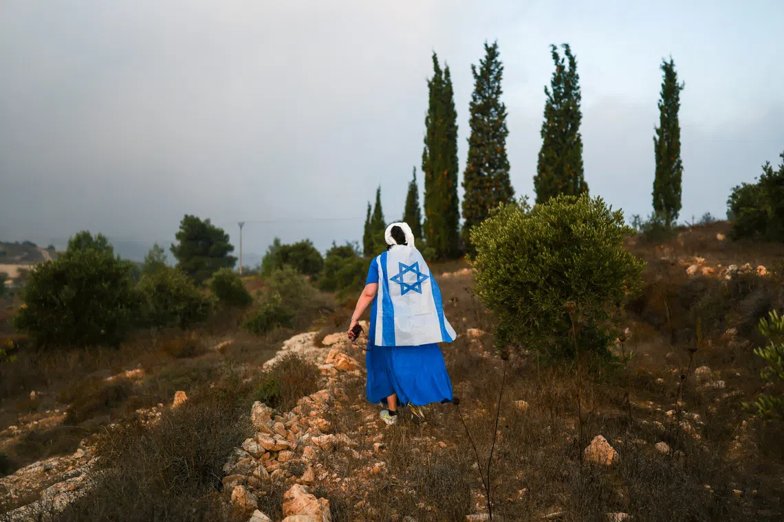 A Jewish settler walks towards olive trees owned by Palestinians due to be harvested, near the Israeli settlement Neve Daniel, in the Israeli-occupied West Bank, October 12, 2026. REUTERS/Ronen Zvulun