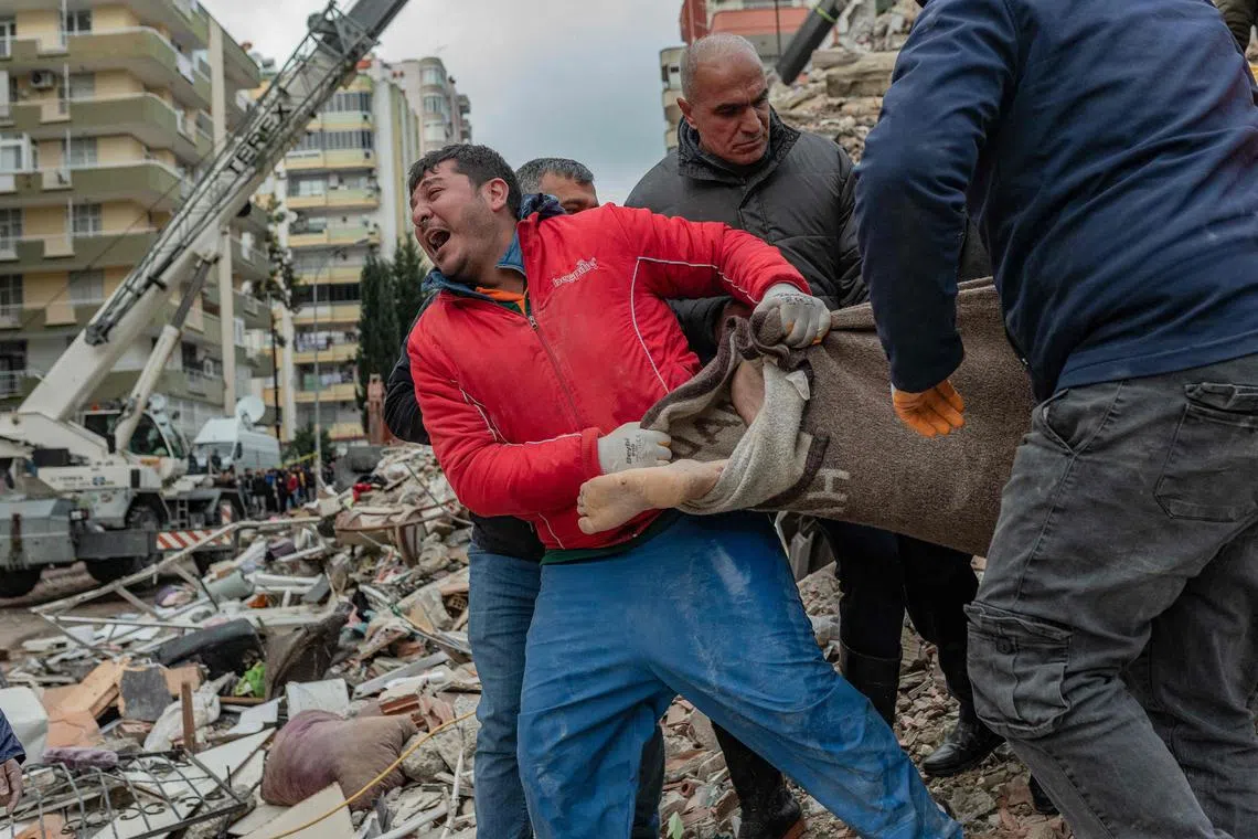 A rescuer reacts as he carries a body found in the rubble in Adana, Turkey, on Feb 6, 2023, after a 7.8-magnitude earthquake struck the country's south-east. 