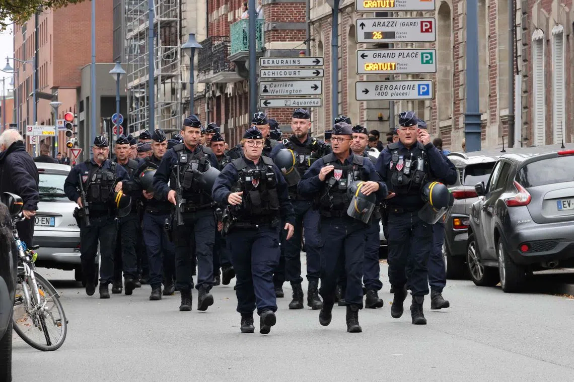 CRS riot police arrive to cordon off an area near the  Gambetta high school in Arras, northeastern France on October 13, 2023, after a teacher was killed and two other people severely wounded in a knife attack. A man of Chechen origin stabbed to death a teacher and severely wounded two other adults on Ocotber 13 at a school in northeastern France, with prosectors opening a probe into a suspected act of terror. (Photo by DENIS CHARLET / AFP)