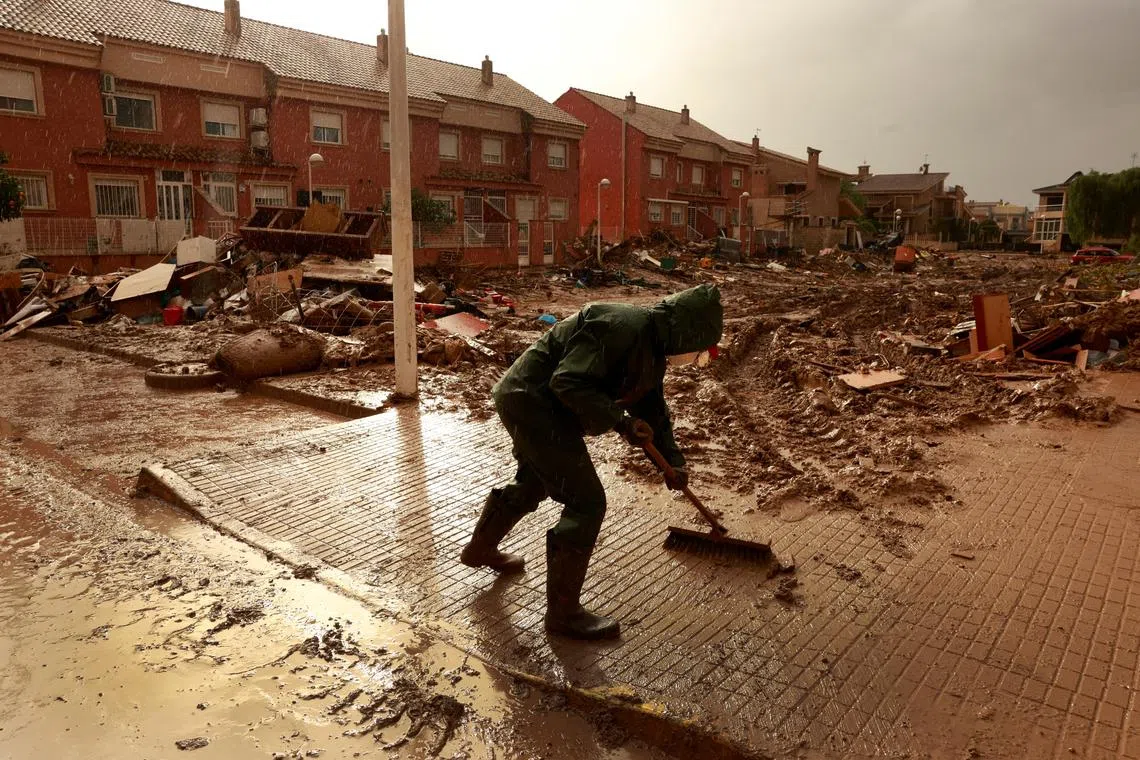 A volunteer cleans muddy water following catastrophic flooding, as Spain braces for more torrential rain, in Paiporta, Valencia, Spain on Nov 13.