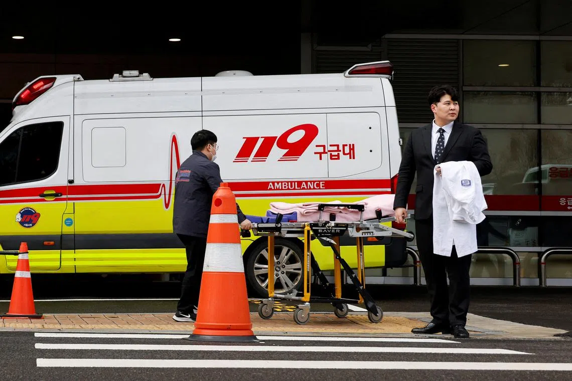 FILE PHOTO: FILE PHOTO: Ryu O. Hada, 25, one of thousands of South Korean trainee doctors who resigned en masse to protest the government's medical policy, holds his white coat in front of the hospital where he worked in Seoul, South Korea, February 25, 2024. REUTERS/Kim Soo-Hyeon/File Photo