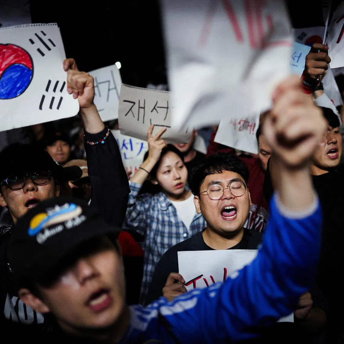 Demonstrators holding signs early on June 6 reading, "Rerun election", outside a vote-counting centre in Seoul, South Korea. PHOTO: REUTERS