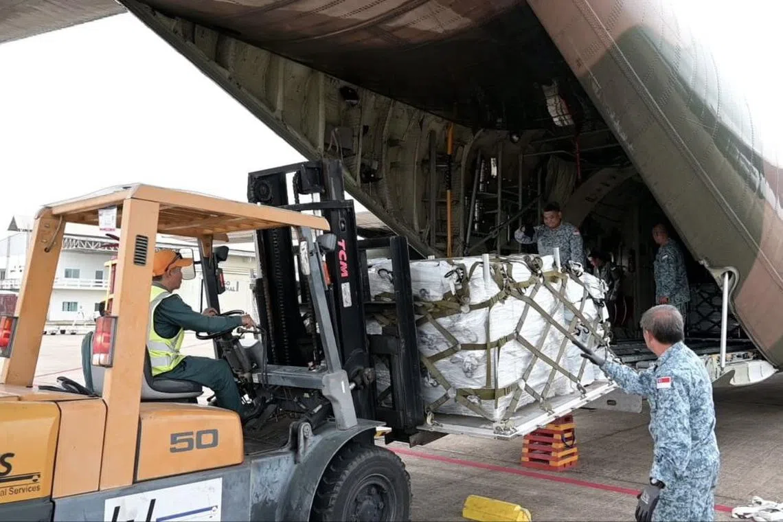 Personnel from the Republic of Singapore Air Force (RSAF) unloading the humanitarian aid supplies from the C-130 transport plane in Vientiane, Laos.