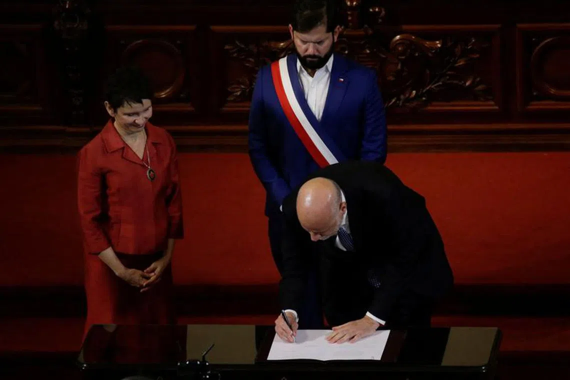 Minister Secretary General, Alvaro Elizalde signs the new Constitution draft as Chile’s President Gabriel Boric and Minister of Interior, Carolina Toha look on, this is the second Constitution draft by the Constitutional Council after the first one was rejected by voters in 2022, in Santiago, Chile November 7, 2023. REUTERS/Sofia Yanjari