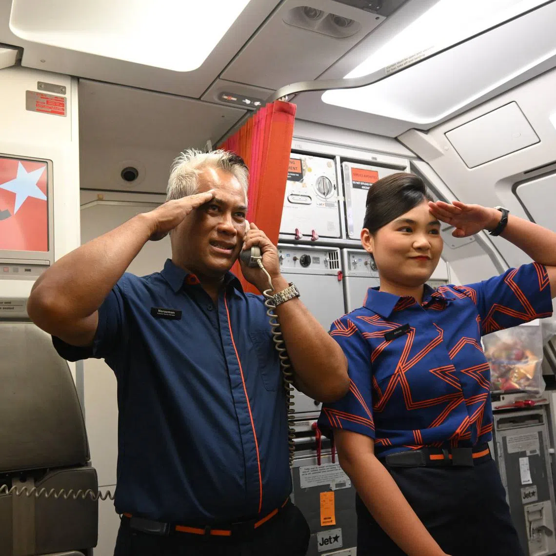 Jetstar Asia in-flight customer service manager Norazman Sapiie (left) speaking over the intercom during the airline's last scheduled flight on July 31.