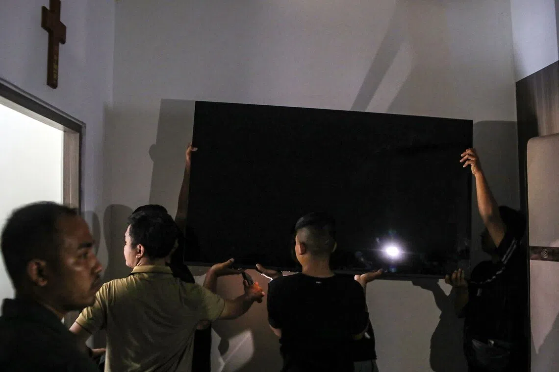 Officials carry away a large-screen television from one of the “villas” in the Cibinong men’s prison, where inmates allegedly paid rent for the luxury accommodation.