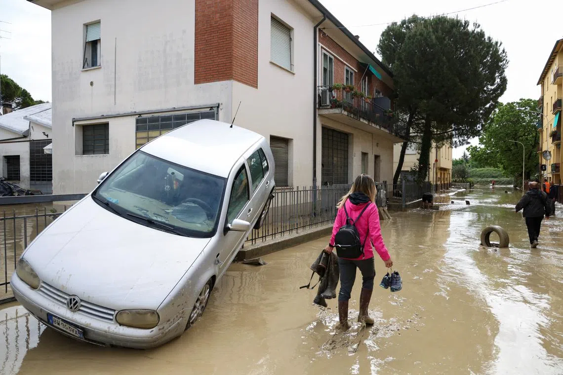People walk through muddy water after heavy rains hit Italy's Emilia Romagna region, in Faenza, Italy, May 18, 2023. 