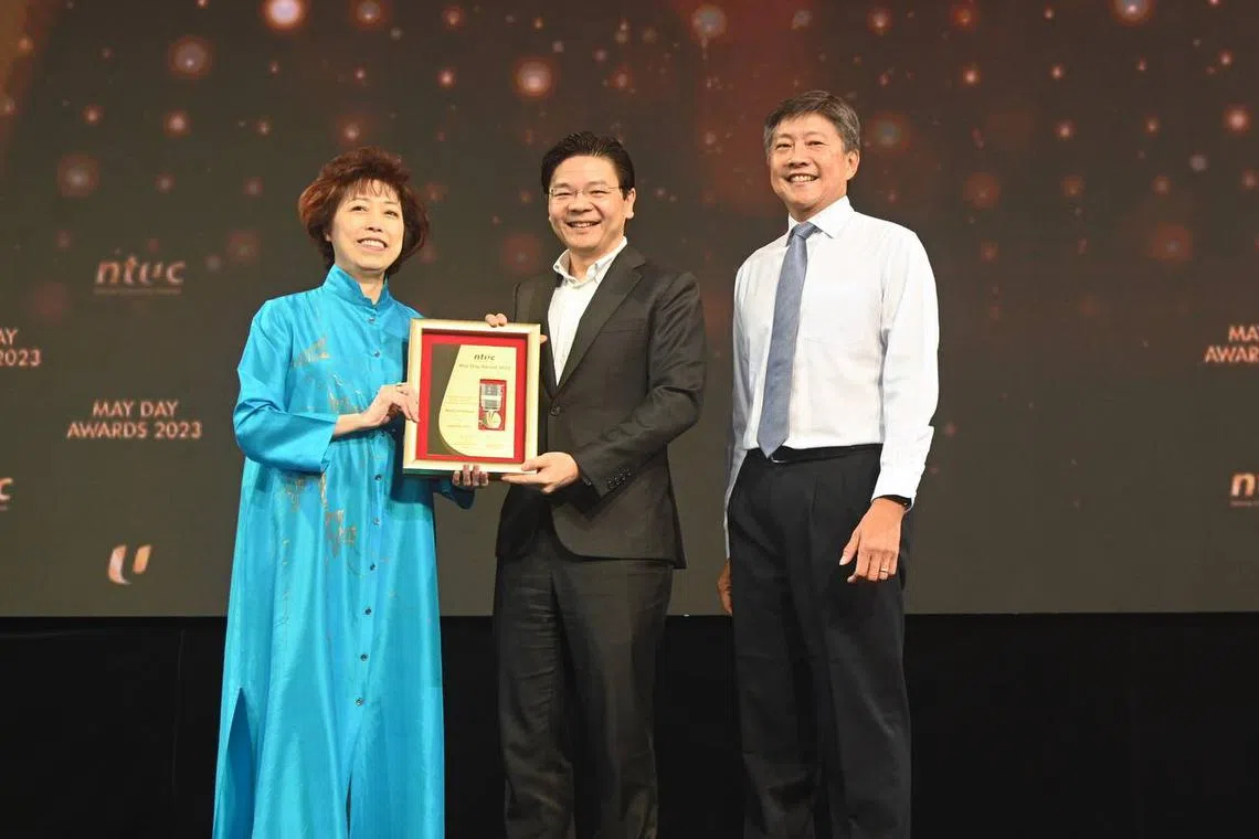 DPM Lawrence Wong (centre) receiving the Medal of Honour from NTUC president Mary Liew (left) and secretary-general Ng Chee Meng.
