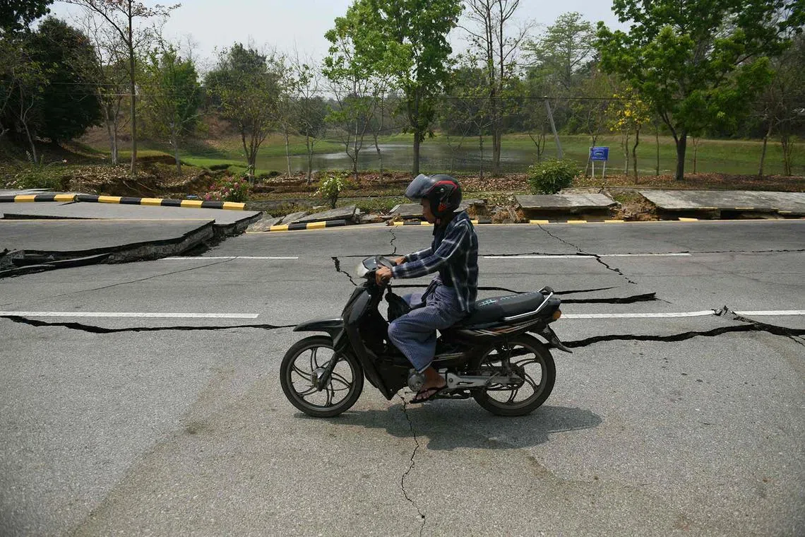 A motorcyclist riding past a damaged road in Naypyidaw on March 28, 2025, after an earthquake rocked central Myanmar, buckling roads, damaging buildings and forcing people to flee into the streets.