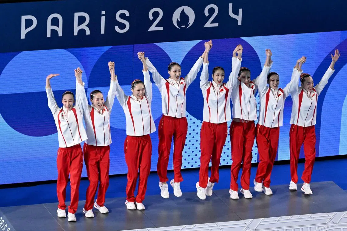 China's gold-medal winning team celebrate on the podium after their artistic swimming victory.