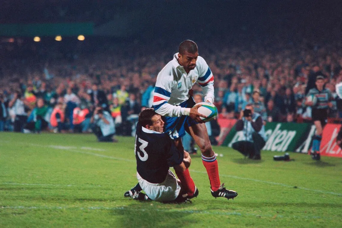 French right wing Emile N'Tamack is tackled by Scotland's centre Scott Hastings as he scores a try in the last minute of the decisive pool D Rugby World Cup at Loftus in Pretoria on June 3, 1995.