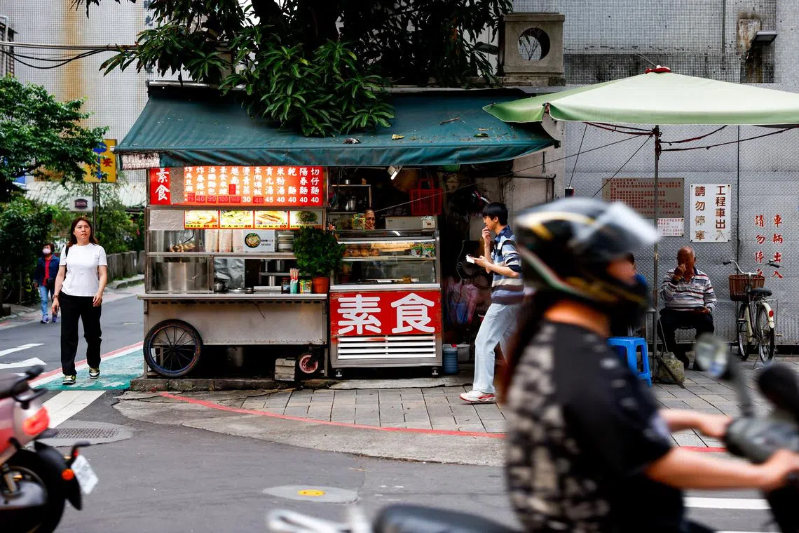 People walk near a food stall on a corner of a street in Taipei,Taiwan April 8, 2025. REUTERS/Ann Wang