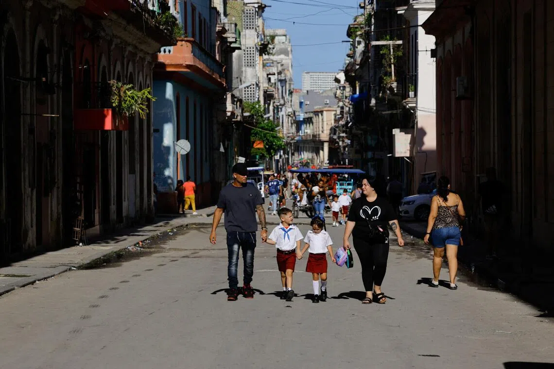 Parents walk with their children in a street as students attend the first day of the 2026-2027 school year amid a severe economic crisis.