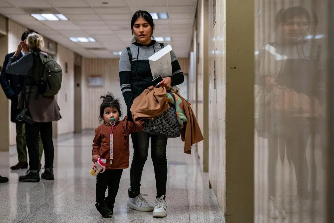 A woman waits with a child at an elevator bank at U.S. immigration court in Manhattan, in New York City, US, on Nov 6, 2025.