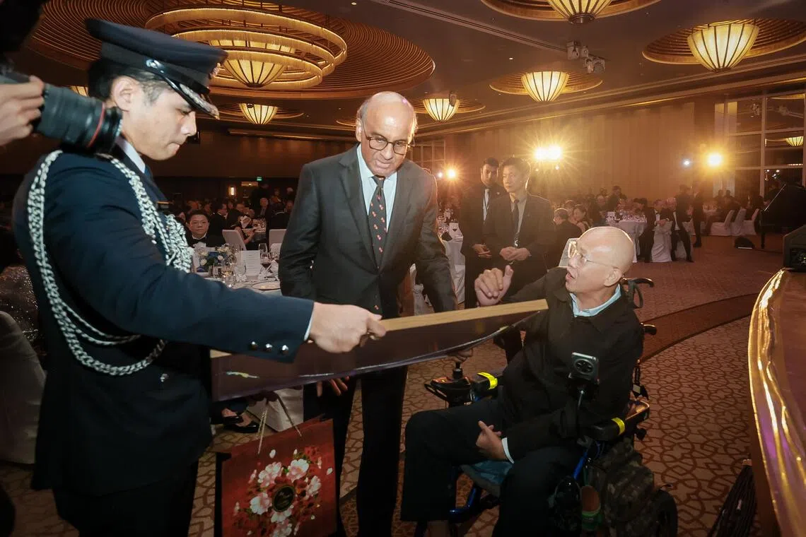 NCCS patient Allan Soh presenting a painting done by himself to President Tharman Shanmugaratnam at the NCCS 25th Anniversary Charity Dinner held at The Ritz Carlton, Millenia Singapore on Sept 28.