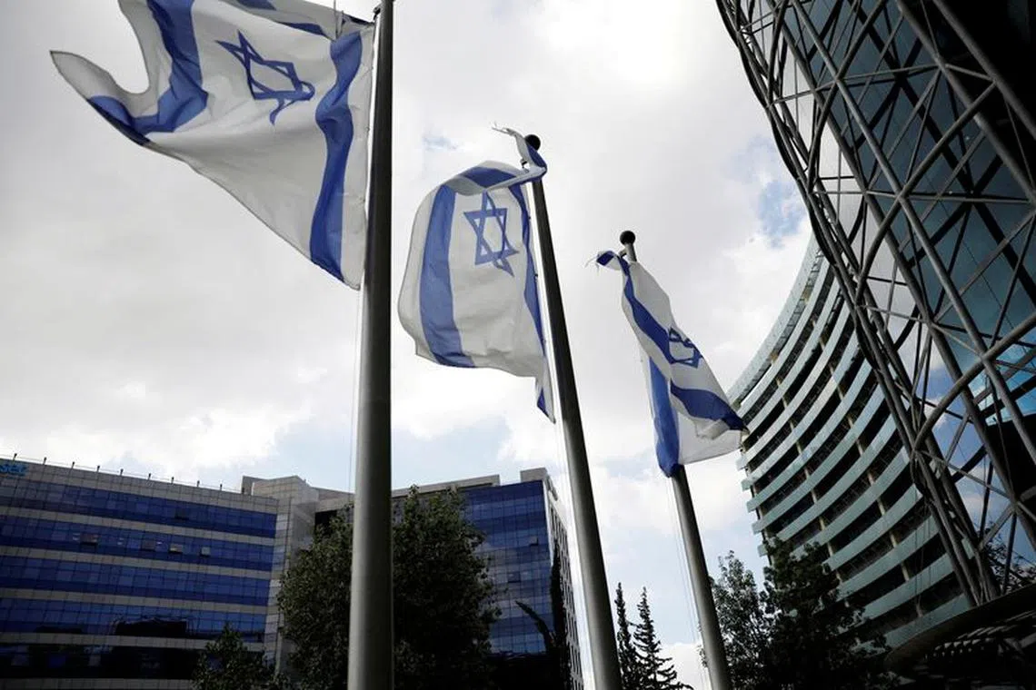 FILE PHOTO: Israeli national flags flutter near office towers at a business park also housing high tech companies, at Ofer Park in Petah Tikva, Israel August 27, 2020. REUTERS/Ronen Zvulun/File Photo