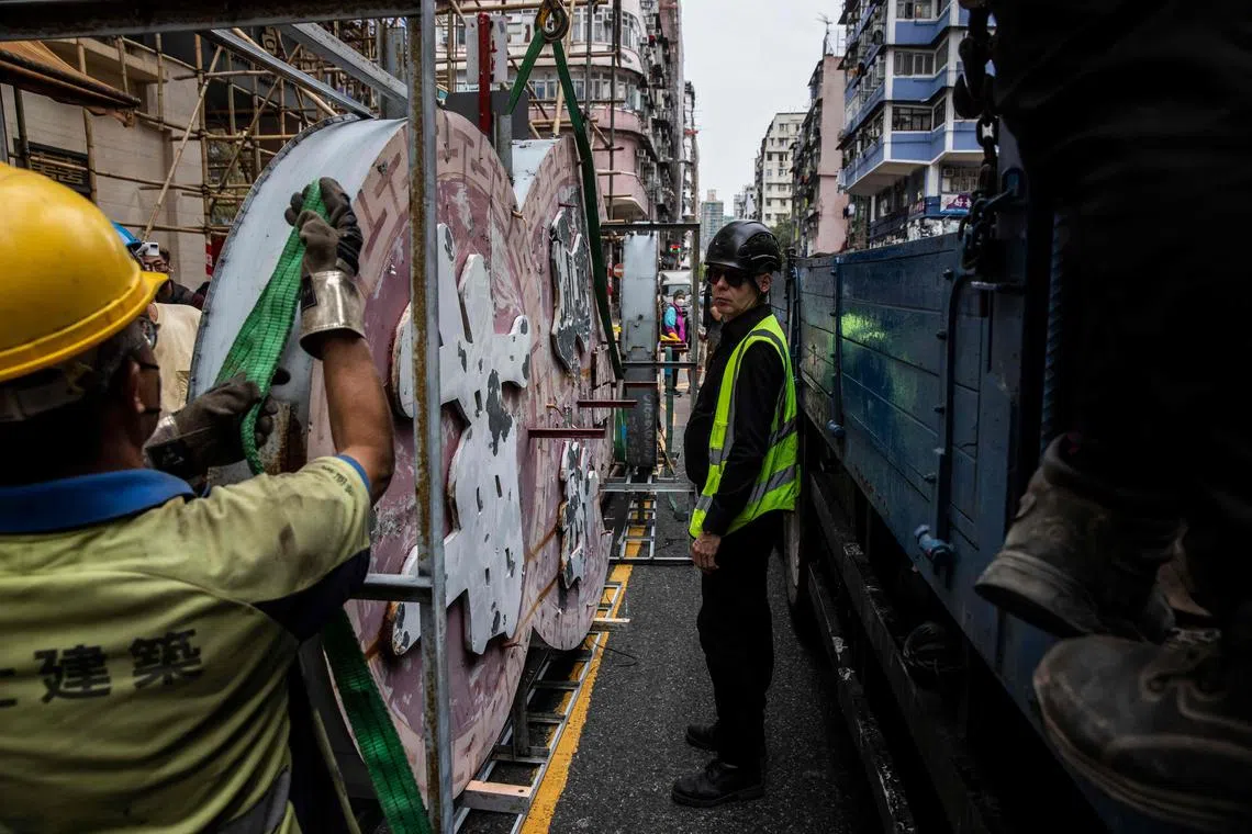 A worker (C) with conservation group Tetra Neon Exchange (TNX) monitoring the removal of the Nam Cheong Pawn Shop neon sign, March 13, 2023. 