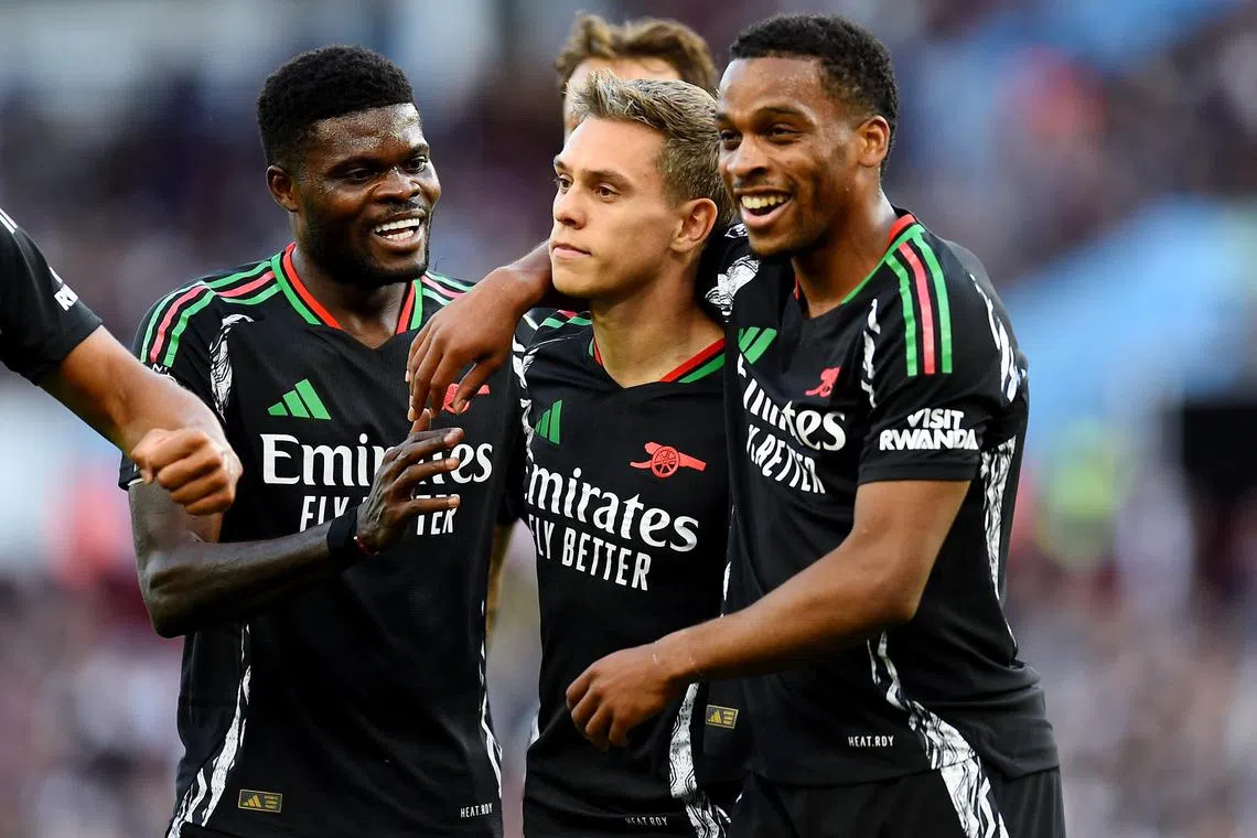 Leandro Trossard celebrates scoring  Arsenal's first goal with Thomas Partey and Jurrien Timber.