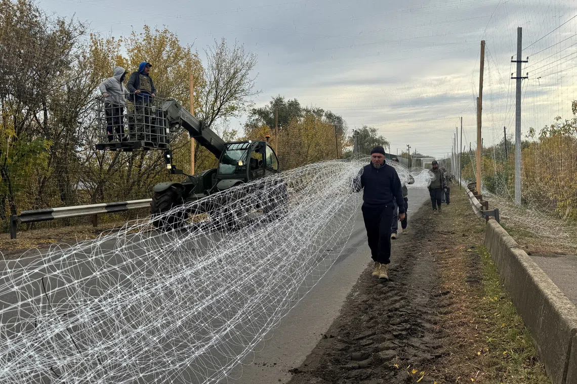 Ukrainian servicemen install anti-drone nets over a road, amid Russia's attack on Ukraine, near the frontline town of Dobropillia in Donetsk region, Ukraine October 8, 2025. REUTERS/Stringer
