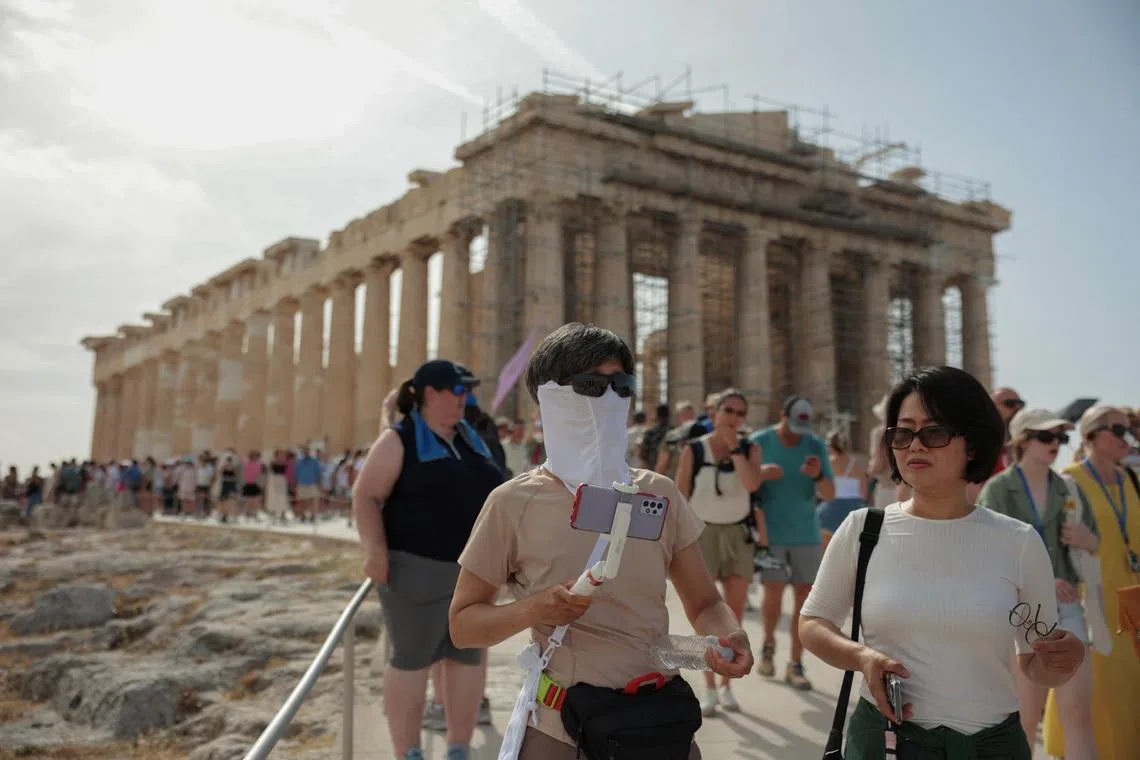 Tourists visit the Parthenon temple atop the famous Acropolis before it closes due to a heatwave, in Athens, Greece, on June 13.