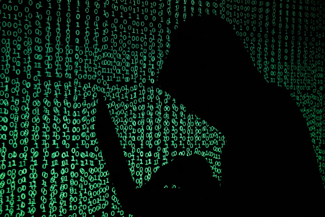 FILE PHOTO: A hooded man holds a laptop computer as cyber code is projected on him in this illustration picture taken on May 13, 2017. REUTERS/Kacper Pempel/Illustration/File Photo