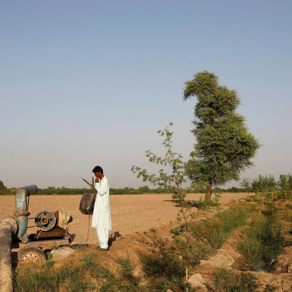 A farmer stands beside a draining pump following rains and floods during monsoon season in Kunri, Pakistan, on Oct 15, 2022.