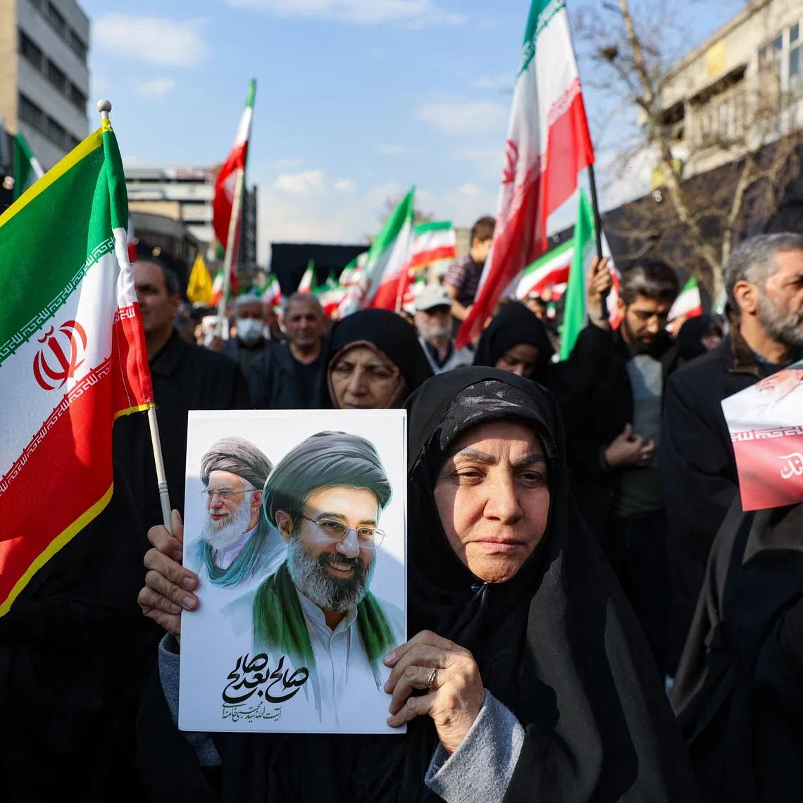 A woman holds a placard with an image of Iran's new supreme leader Mojtaba Khamenei alongside late Iranian Supreme Leader Ayatollah Ali Khamenei in Tehran, Iran, March 9, 2026. Majid Asgaripour/WANA (West Asia News Agency) via REUTERS