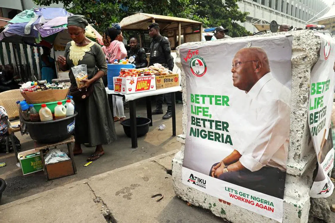 FILE PHOTO: A street vendor is pictured next to a campaign poster of Atiku Abubakar, leader of the People's Democratic Party (PDP) in Lagos, Nigeria, February 12, 2019. Picture taken February 12, 2019. REUTERS/Luc Gnago/File Photo