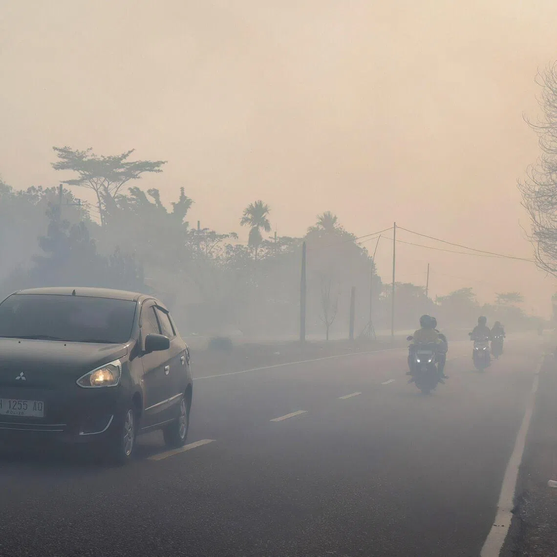 Motorists drive with headlights on a haze-shrouded road in Palangka Raya city, central Kalimantan on Aug 20.