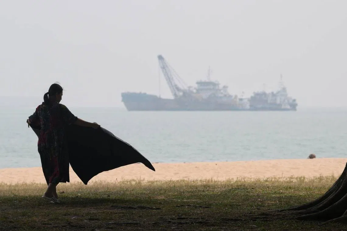 A woman laying out her picnic mat at East Coast Park at about 3pm on Oct 7. The 24-hour PSI in the east was 117.