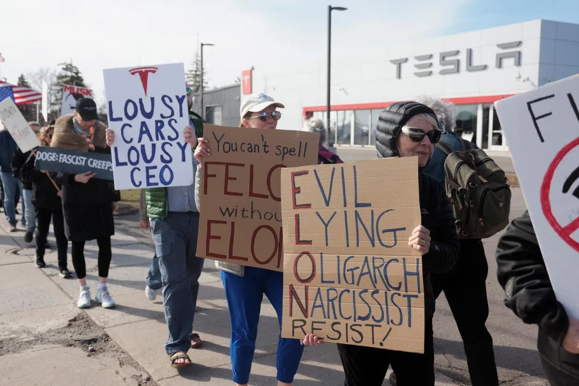FILE PHOTO: Demonstrators protest against Elon Musk in front of a Tesla dealership in Ann Arbor, Michigan, U.S., March 21, 2025.     REUTERS/Rebecca Cook/File Photo
