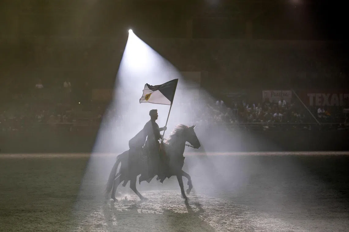 A member of the Ordoglovasok (Devil Riders) acrobatic riding school of Gyor carries a flag during the Lipica International Historical Equestrian Gala in the Lipizzan Equestrian Centre in Szilvasvarad, northern Hungary, on August 19, 2023.