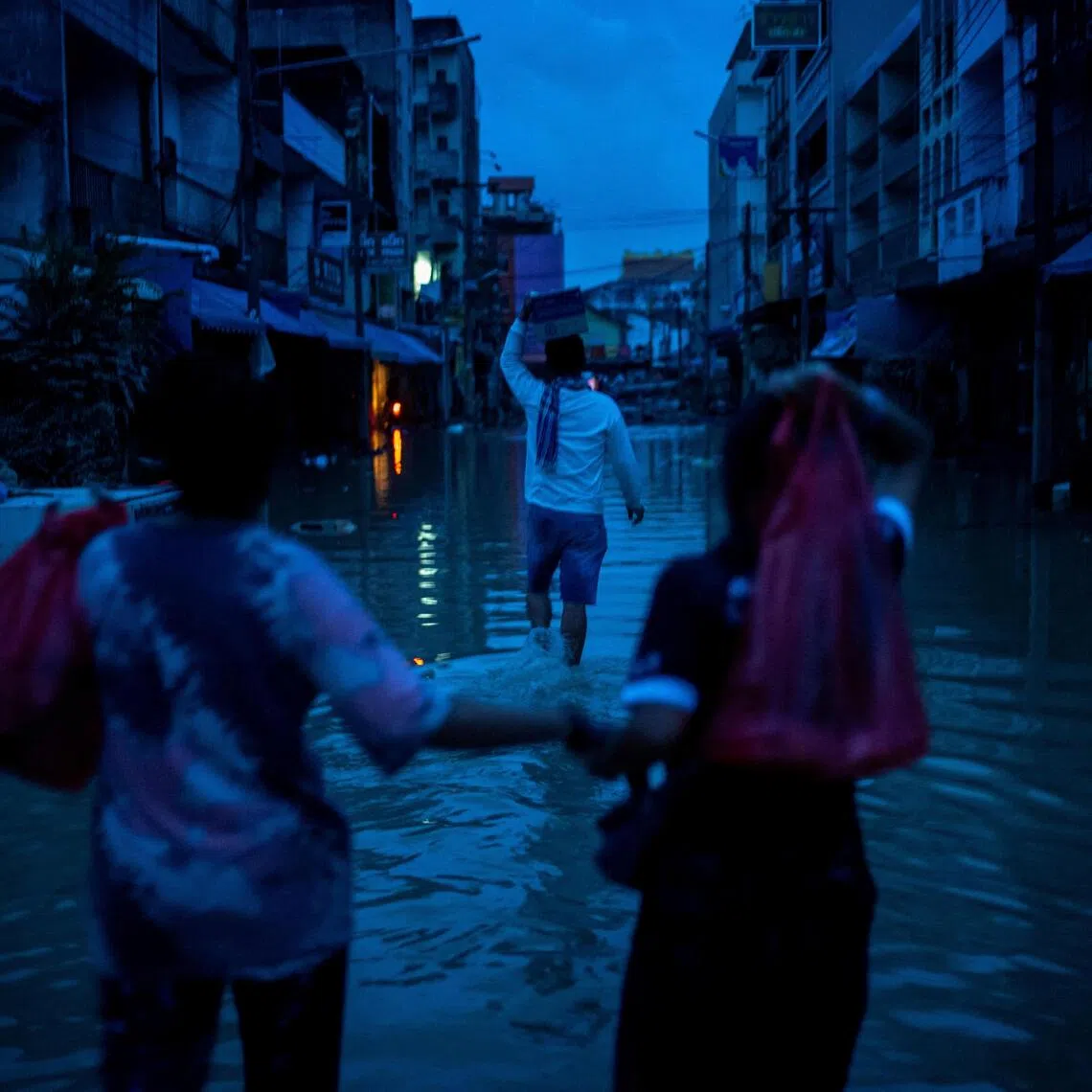 Relatives carry relief supplies as they visit their family members trapped at a house after flooding in Hat Yai.