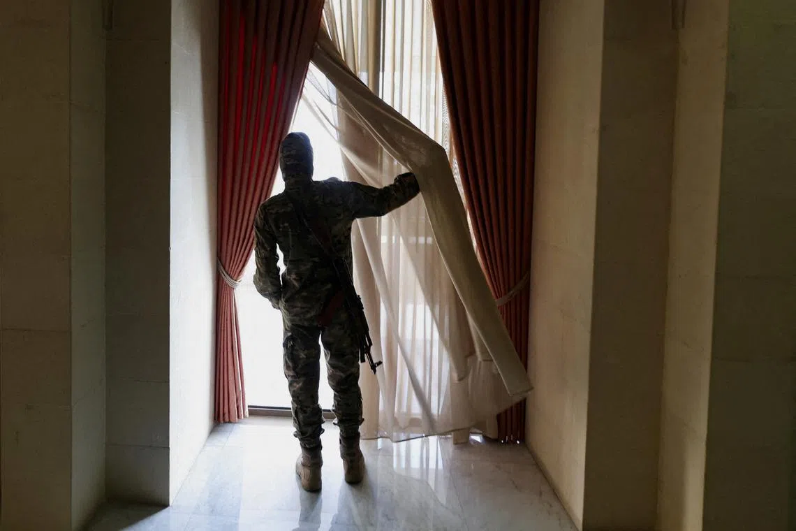 A rebel fighter looking through a window inside the welcoming hall in the Presidential Palace known as Qasr al-Shaab "People's Palace", after rebels seized the capital and ousted Syria's Bashar al-Assad, in Damascus, Syria Dec 10, 2024. 