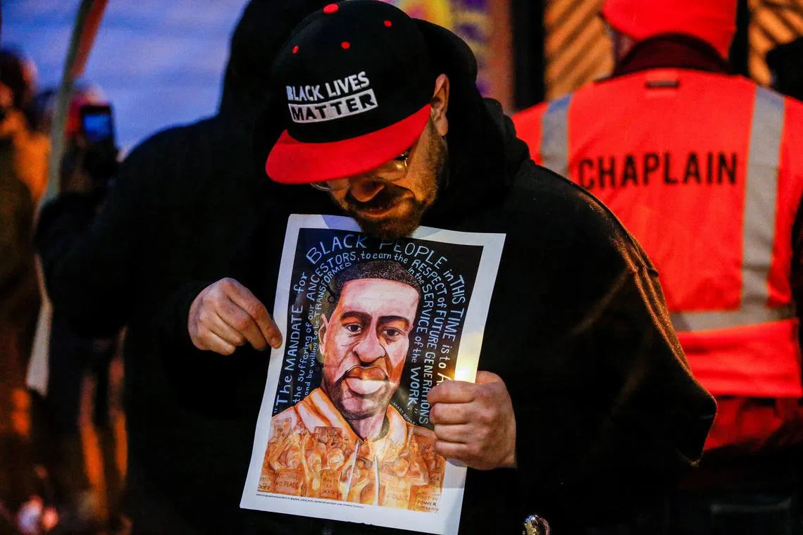 FILE PHOTO: A man holds an image of George Floyd at a vigil on the second anniversary of the death of Floyd, a black man who was killed in 2020 by white police officer Derek Chauvin by kneeling on his neck, in Minneapolis, Minnesota, U.S. May 25, 2022. REUTERS/Eric Miller/File Photo