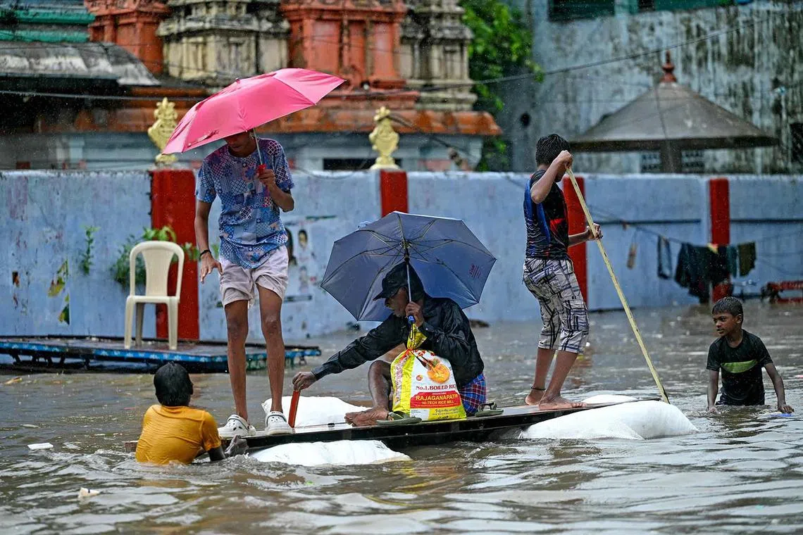 TOPSHOT - People make their way through a flooded street amid heavy rainfall in Chennai on October 15, 2024. (Photo by R.Satish BABU / AFP)