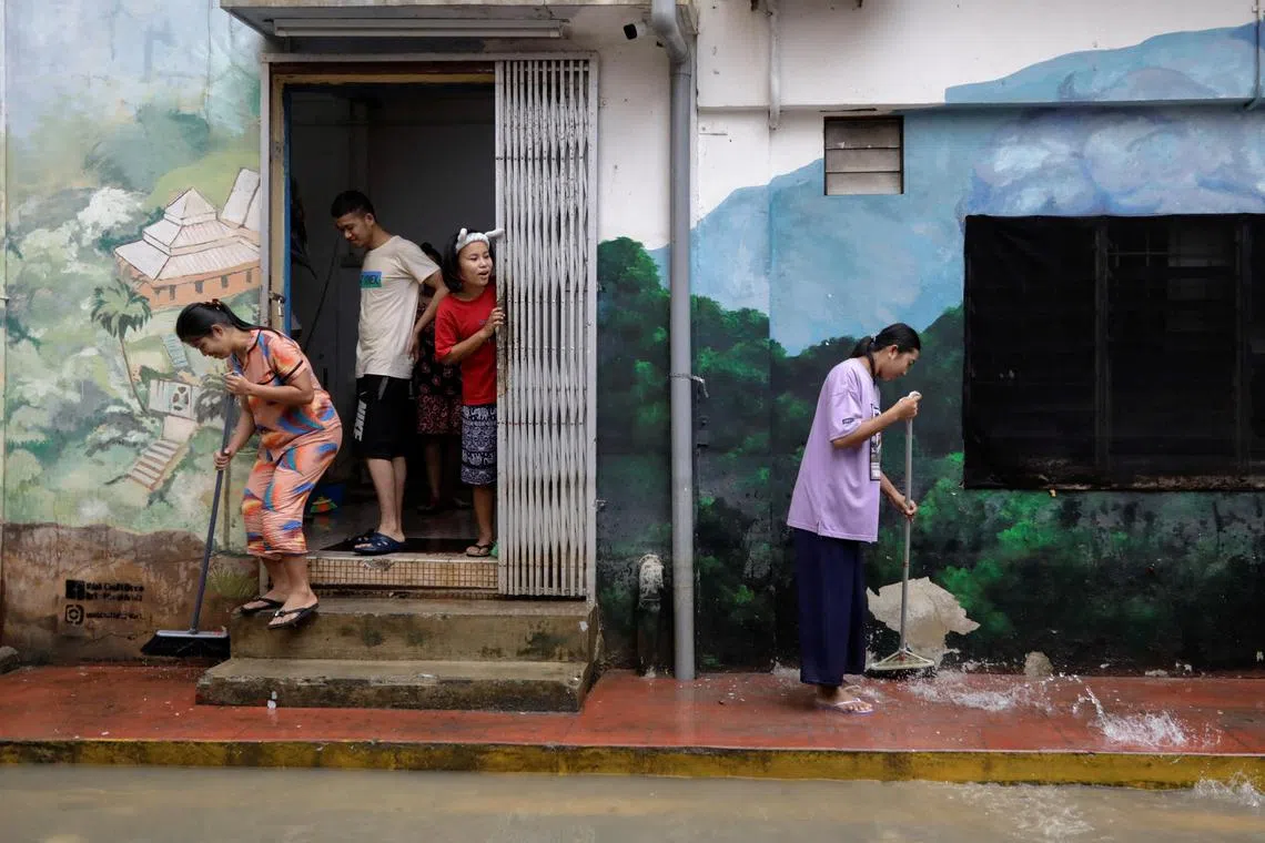 People clean the back-alley of shophouse as the floodwaters recede, in Kota Tinggi, Johor.