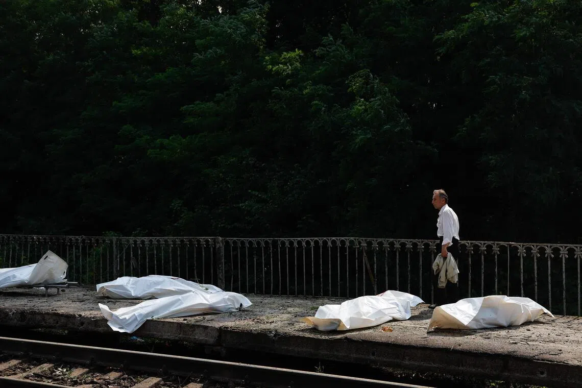 A man walking past plastic bags containing the bodies of people killed at a railway station in the Kyiv region on Aug 5, during Russian ballistic missile and drone strikes.