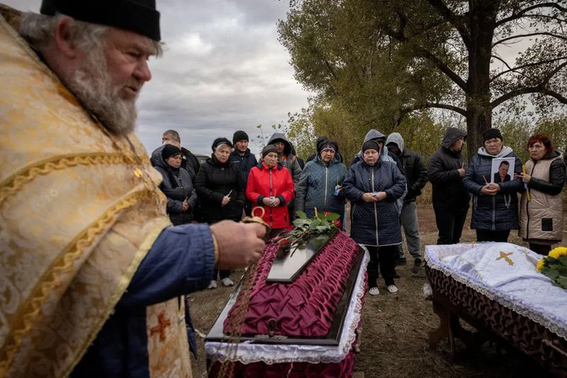 FILE PHOTO: Family and relatives attend the funeral of Iryna Kharbaka and Oleksandr Khodak who were killed in a Russian missile attack, amid Russia's ongoing invasion of Ukraine, at the village cemetery, in the village of Hroza, near Kharkiv, Ukraine October 9, 2023. REUTERS/Thomas Peter/File Photo