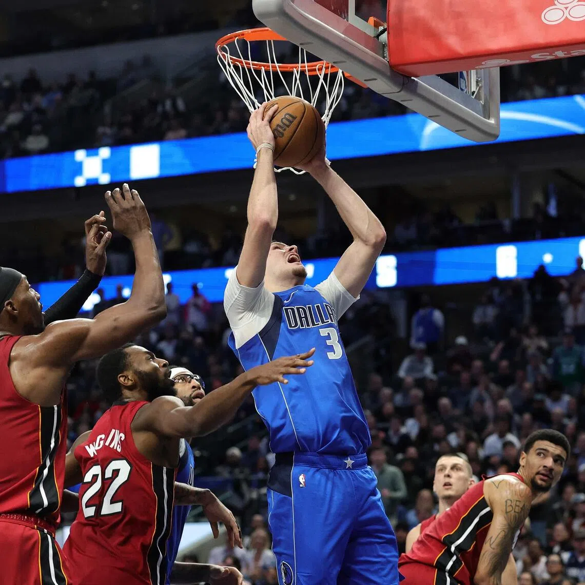 Cooper Flagg of the Dallas Mavericks is defended by Andrew Wiggins and Bam Adebayo of the Miami Heat during the second half at American Airlines Center.
