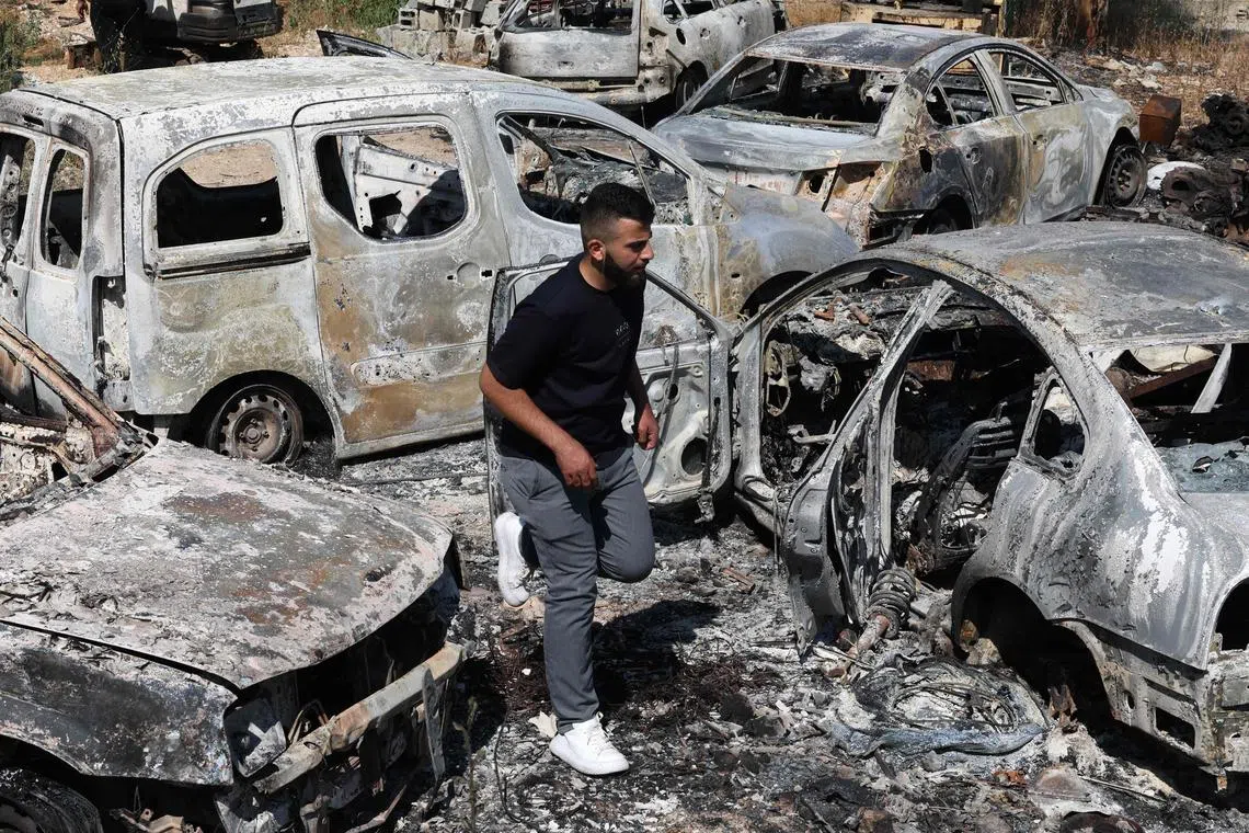 A man walks past cars reportedly set ablaze by Israeli settlers in the occupied West Bank.