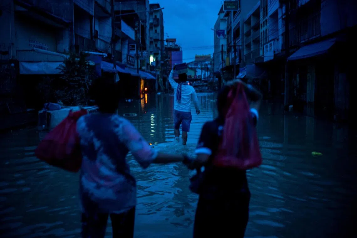 Relatives carry relief supplies as they visit their family members trapped at a house after flooding in Hat Yai.