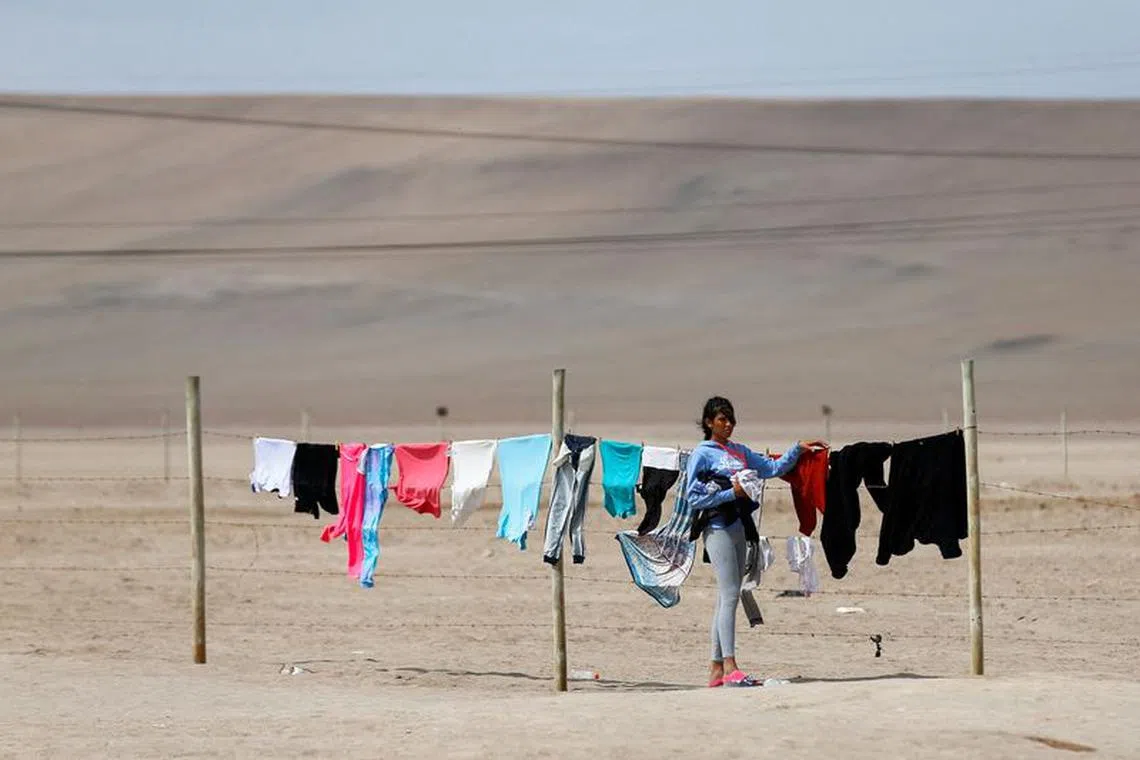 FILE PHOTO: An undocumented migrant hangs clothes on a makeshift clothesline as migrants remain stuck in Chile after Peru refused to open its borders to migrants, in Chacalluta area, Arica, Chile May 6, 2023. REUTERS/Hugo Curotto/File Photo