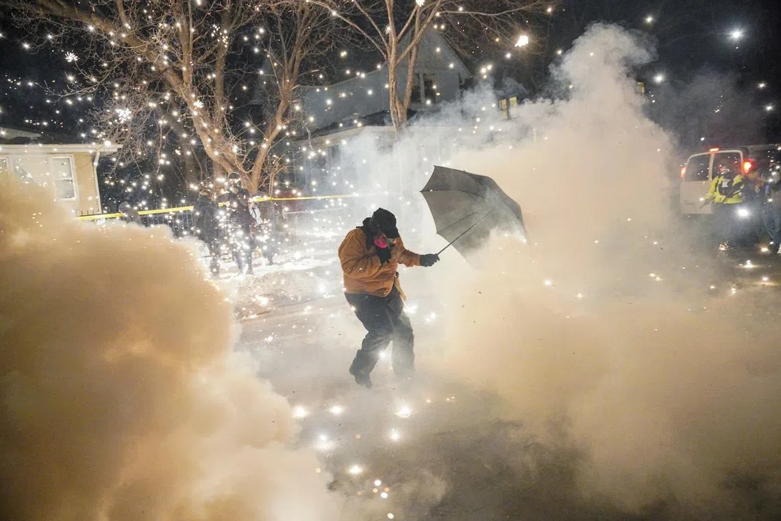 A protesting community member attempts to protect themselves as federal agents fire munitions and pepper balls, as tensions rise after federal law enforcement agents were involved in a shooting incident, a week after a U.S. Immigration and Customs Enforcement (ICE) agent fatally shot Renee Nicole Good, in north Minneapolis, Minnesota, U.S., January 14, 2026. REUTERS/Ryan Murphy