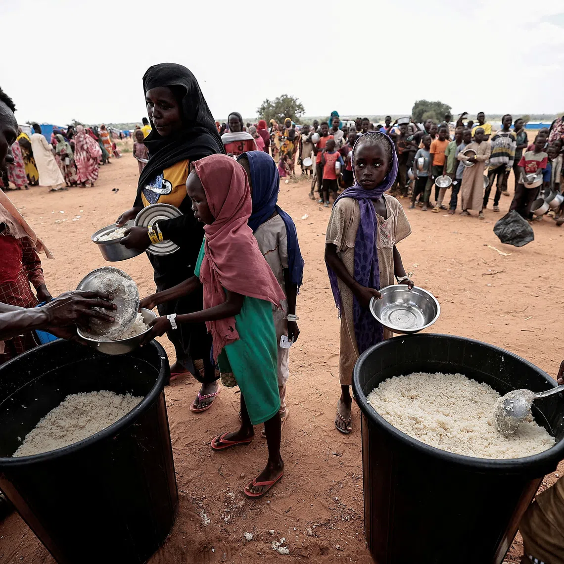FILE PHOTO: Sudanese people, who fled the conflict in Geneina in Sudan's Darfur region, receive rice portions from Red Cross volunteers in Ourang on the outskirts of Adre, Chad July 25, 2023. REUTERS/Zohra Bensemra/File Photo