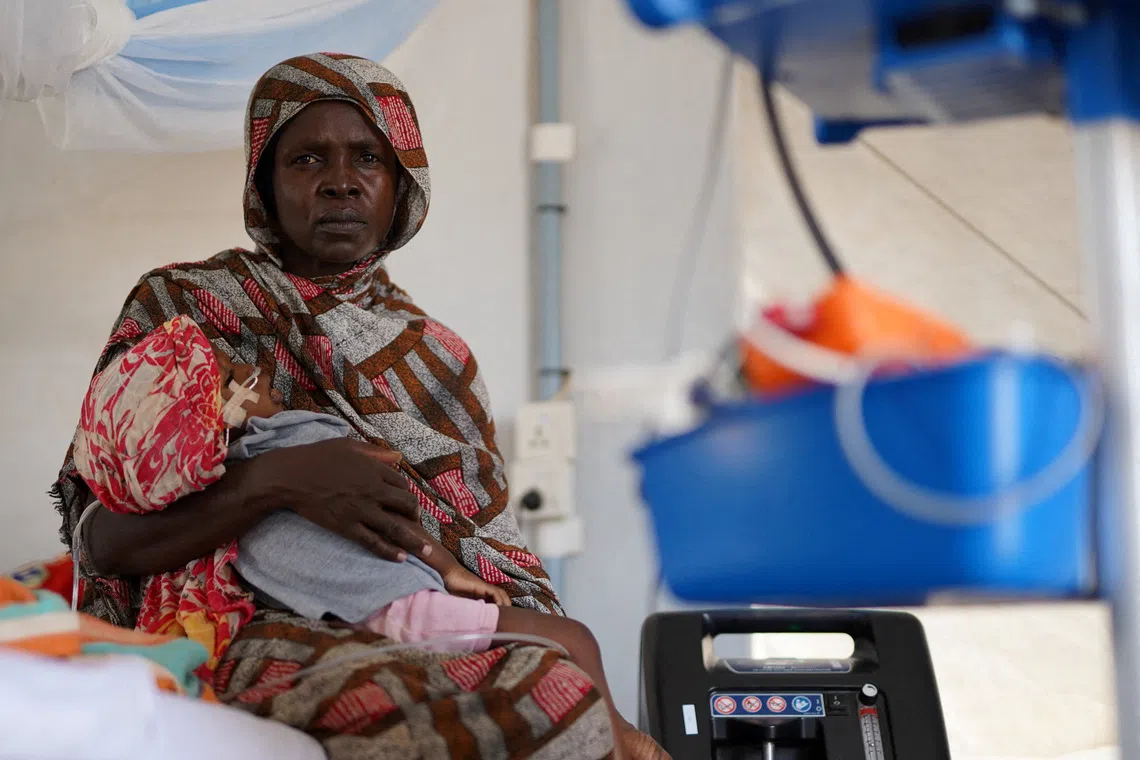 FILE PHOTO: An injured displaced Sudanese woman who fled violence in al-Fashir receives treatment while carrying her child at a makeshift clinic run by Medecins Sans Frontieres (MSF), amid ongoing clashes between the paramilitary Rapid Support Forces (RSF) and the Sudanese army, in Tawila, North Darfur, Sudan November 3, 2025. REUTERS/Mohamed Jamal/File Photo