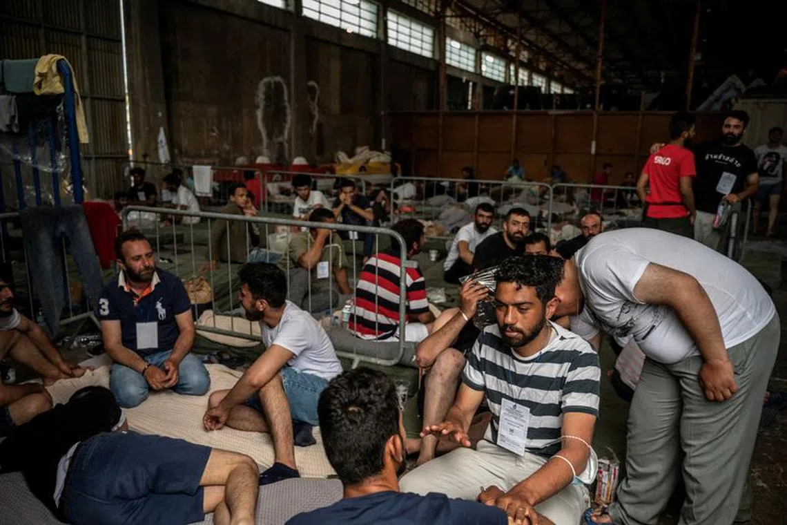 Migrants who were rescued at open sea off Greece along with other migrants, after their boat capsized, are seen inside a warehouse, used as shelter, at the port of Kalamata, Greece, June 15, 2023. Angelos Tzortzinis/Pool via REUTERS/File Photo