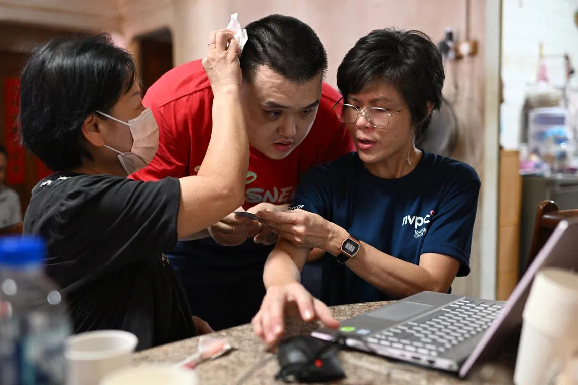 (From left) Madam Annie Chang and her son Kelvin with Ms Lee Siew Yian, a senior manager at NVPC, with a laptop that was donated by a friend of Ms Lee. 