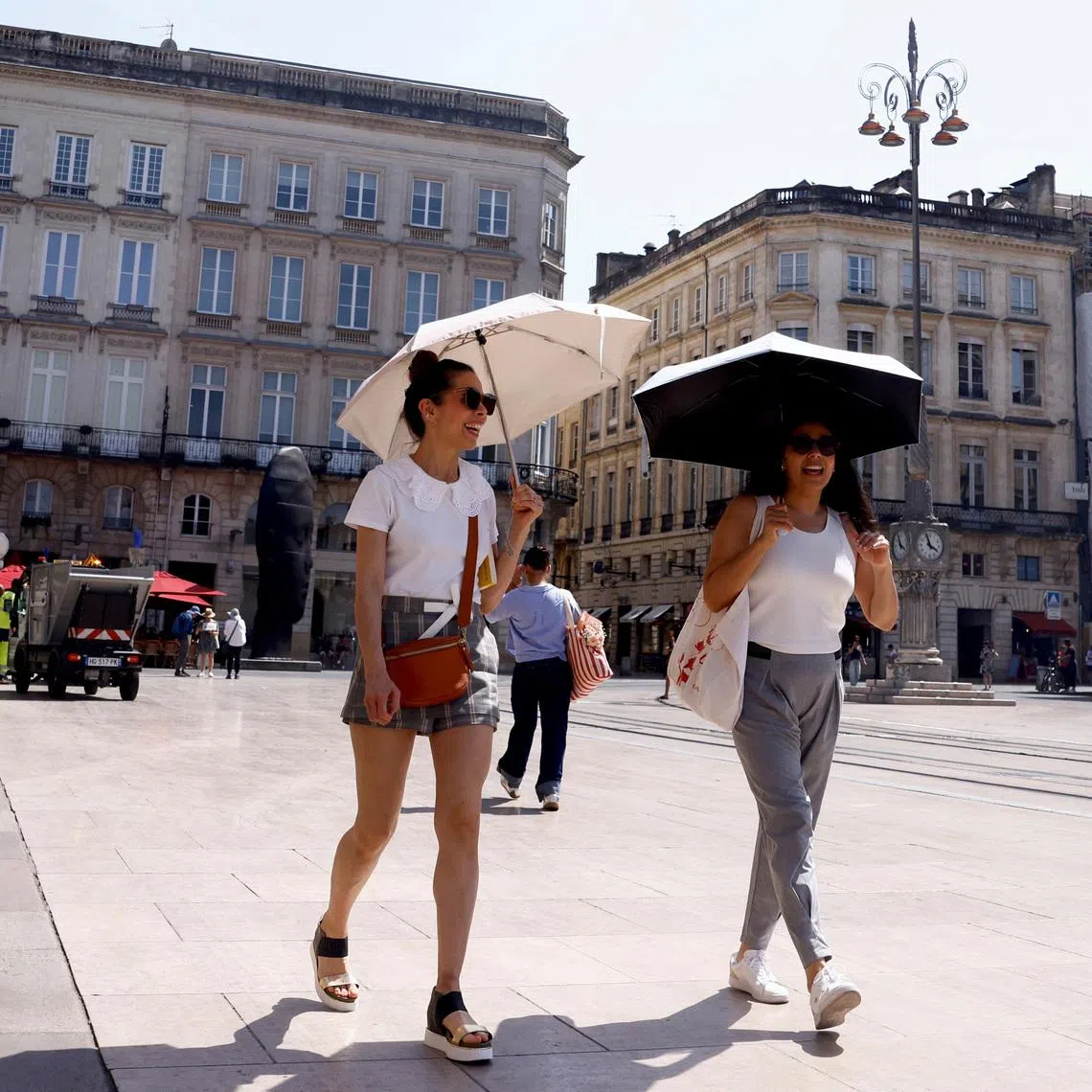 Women walk holding umbrellas to protect from the sun amid a heatwave in Bordeaux, France, on May 28.